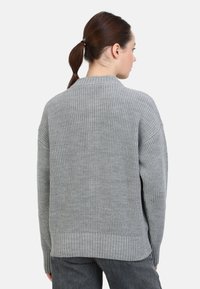 Suéter gris de punto con textura acanalada, mangas anchas y cuello redondo. Presenta un dobladillo recto y un diseño de corte relajado.