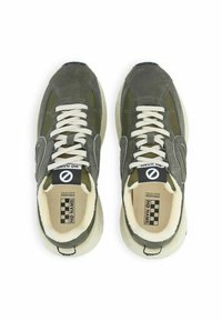 Baskets vertes avec une tige en daim et en mesh, lacets blancs et étiquette de logo noir et blanc. Semelle épaisse avec un design texturé, bout arrondi.
