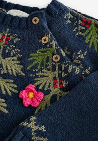 Navyfarbener Strickpullover mit grüner Blattdekoration und roten Akzenten. Mit einer applizierten rosa Blume und Holzknöpfen am Kragen.