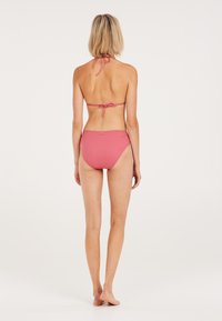 Růžový bikinový set s halter krkem, který má zavazování, a vysokými pasovými kalhotkami s žebrovanou strukturou, které se pyšní texturovaným materiálem a jednoduchým designem.