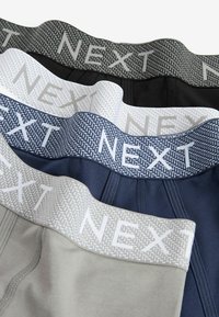 Vier Paare Herrenunterwäsche mit elastischem Bund in Grau, Marineblau, Schwarz und Hellgrau, versehen mit dem strukturierten "NEXT"-Branding.