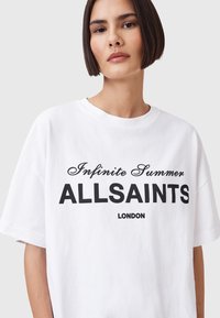 Witte katoenen T-shirt met zwarte tekst: "Infinite Summer ALLSAINTS LONDON." Het shirt heeft een relaxte pasvorm en een ronde hals met korte mouwen.