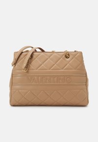 Beige quilted leather handbag with two handles, gold-tone hardware, and embossed branding. Features a textured surface and geometric pattern.