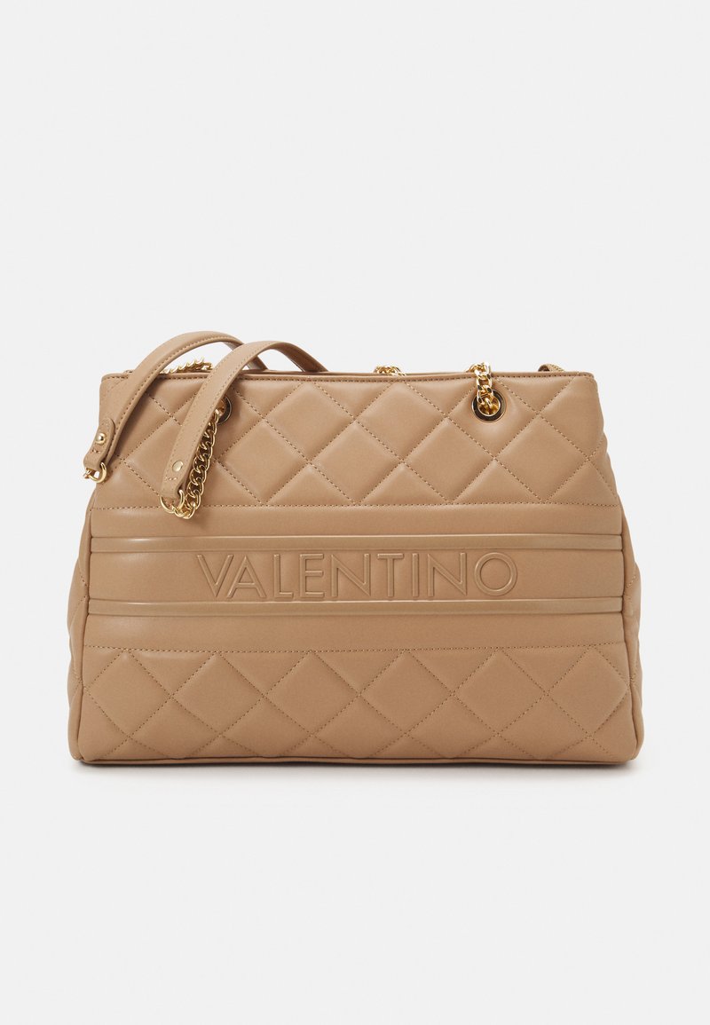 Beige quilted leather handbag with two handles, gold-tone hardware, and embossed branding. Features a textured surface and geometric pattern.