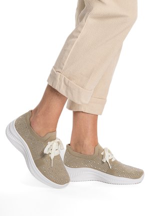 Beige strikkede sneakers med hvide såler og snørebånd, pyntet med små rhinsten, båret med opsmøgede beige kordfløjlsbukser.
