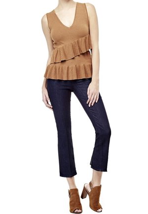Top marrón con textura acanalada y escote en V profundo, con detalles de volantes en capas; combinado con jeans oscuros y recortados y tacones marrones de punta abierta.