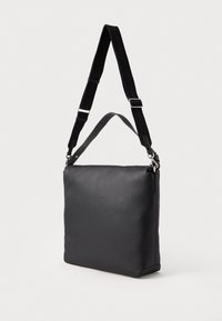 Czarna prostokątna skórzana torba na ramię z regulowanym czarnym materiałowym paskiem i krótkim skórzanym uchwytem, pokazana na jednolitym tle.