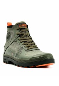 Botte montante verte en matériau synthétique texturé. Présente des accents oranges, un patch logo décoratif et une semelle noire robuste avec des détails orange.