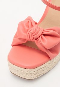 Korálově růžové espadrilky s uzlovou mašlí, vyrobené z hladké kůže, s tkanou jutovou platformou a plochou béžovou stélkou.