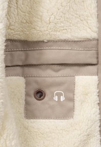 Tan fabric with a soft cream fleece lining; features a brown eyelet and a white headphone logo. Textured and warm design details.