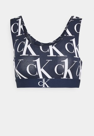 Granatowy stanik sportowy wykonany z elastycznej tkaniny, z białym wzorem logo "ck". Posiada zaokrąglony dekolt i jednolitą talię.