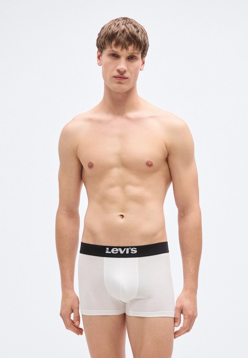 Biele bavlnené boxerky s čiernym elastickým pásom Levi's, s priliehavým strihom a hladkou textúrou, nosené osobou stojacou vzpriamene.
