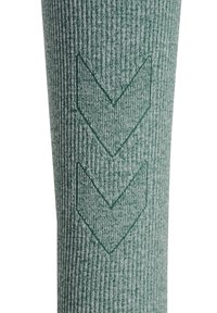 Grijs-groene textuursok met verticale ribbels en twee groene chevronpatronen aan de zijkant, die een opvallend designelement vormen.