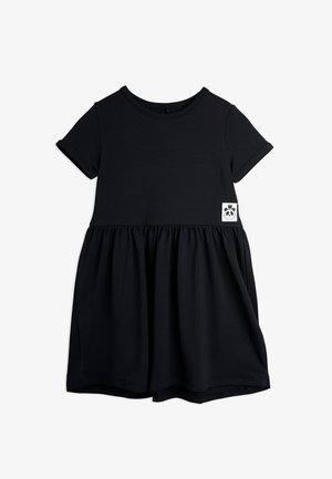 Rochie scurtă neagră din bumbac moale, cu mâneci scurte, având o fustă plisată și un mic logo cu un panda pe un pătrat alb aproape de tiv.