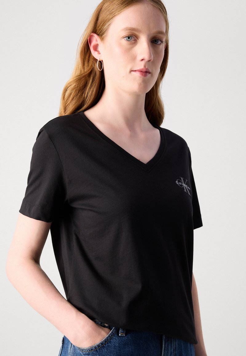 Czaryn bawełniany T-shirt z dekoltem w serek i krótkimi rękawami, z małym graficznym logo na piersi. Teksturowany, luźny krój.