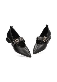 Zapatos de cuero negro con un diseño de punta afilada, que cuentan con una correa con ojales metálicos y un pequeño tacón cuadrado. Textura suave.