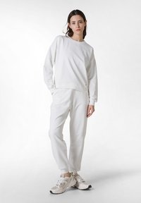 Witte sweatshirt met een ronde halslijn en ribgebreide manchetten, gecombineerd met bijpassende witte joggingbroeken. Relaxte pasvorm met zijzakken. Lichte textuur.
