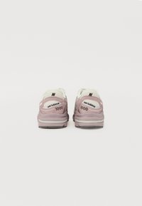 Les baskets New Balance 1000 disposent d'un dessus en mesh rose et blanc, d'une semelle rembourrée et d'un logo brodé sur le talon.