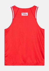 Czerwona bezrękawnik sportowy z białymi paskami na otworach na ramiona i naszywką z logo Nike blisko górnej części kołnierza.