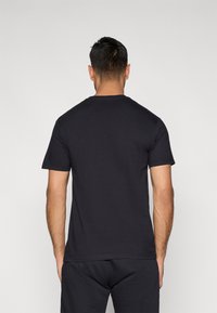 Fekete rövid ujjú pamutpóló kerek nyakkal, sima felülettel és laza fazonnal.