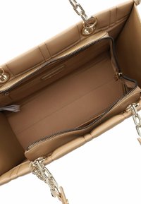 Beige lederen handtas met een gequilt ontwerp, gouden hardware, kettinghengsels en een ruime binnenkant met een ritsvak en een gladde voering.