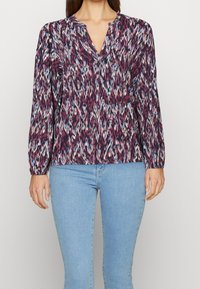 Long-sleeve blouse in patterned fabric with shades of purple, blue, and pink; v-neckline and gathered cuffs; relaxed fit.
