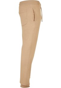 Béžové teplákové kalhoty z měkké bavlněné směsi, s bočními kapsami, vykrojeným střihem nohavic a elastickým pasem se šňůrkou na stažení.