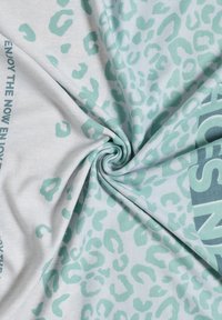 Tissu gris clair avec un motif léopard vert menthe et du texte. La texture est lisse et extensible, ce qui améliore le confort.