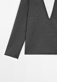 Dark gray long-sleeve shirt with a V-neck layered over a light gray shirt visible at the collar and sleeve ends.