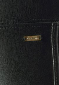 Schwarze Lederbrieftasche mit strukturiertem Oberflächen, goldfarbenem Logo-Schild und sauberem Nähen. Kompaktes Design ohne sichtbare Muster.