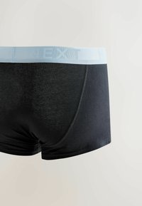 Fekete férfi boxeralsó világoskék elasztikus derékpánttal, amelyen a "NEXT" márkanév dombornyomott. Simább anyagú, testhezálló fazon.