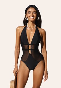 Maillot de bain une pièce noir avec des panneaux en mesh, décolleté en V profond et un centre découpé. Il présente un design à col halter et de hautes ouvertures au niveau des jambes.