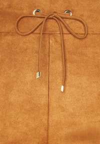 Bruin suede materiaal met een zachte textuur. Voorzien van een trekkoordsluiting die door zilveren metalen ogen is geregen en afgewerkt met vierkante gouden hardware.