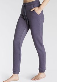 Lila Jogginghose mit Kordelzugbund, zwei seitlichen Taschen und gerippten Knöcheln, aus weichem, dehnbarem Stoff mit glatter Textur.