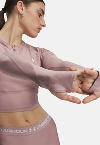 Lichtroze, aansluitend, lang mouwtop met een hoge kraag, voorzien van textuurpanelen en duimholaansluitingen. Draagt met bijpassende high-waisted legging.