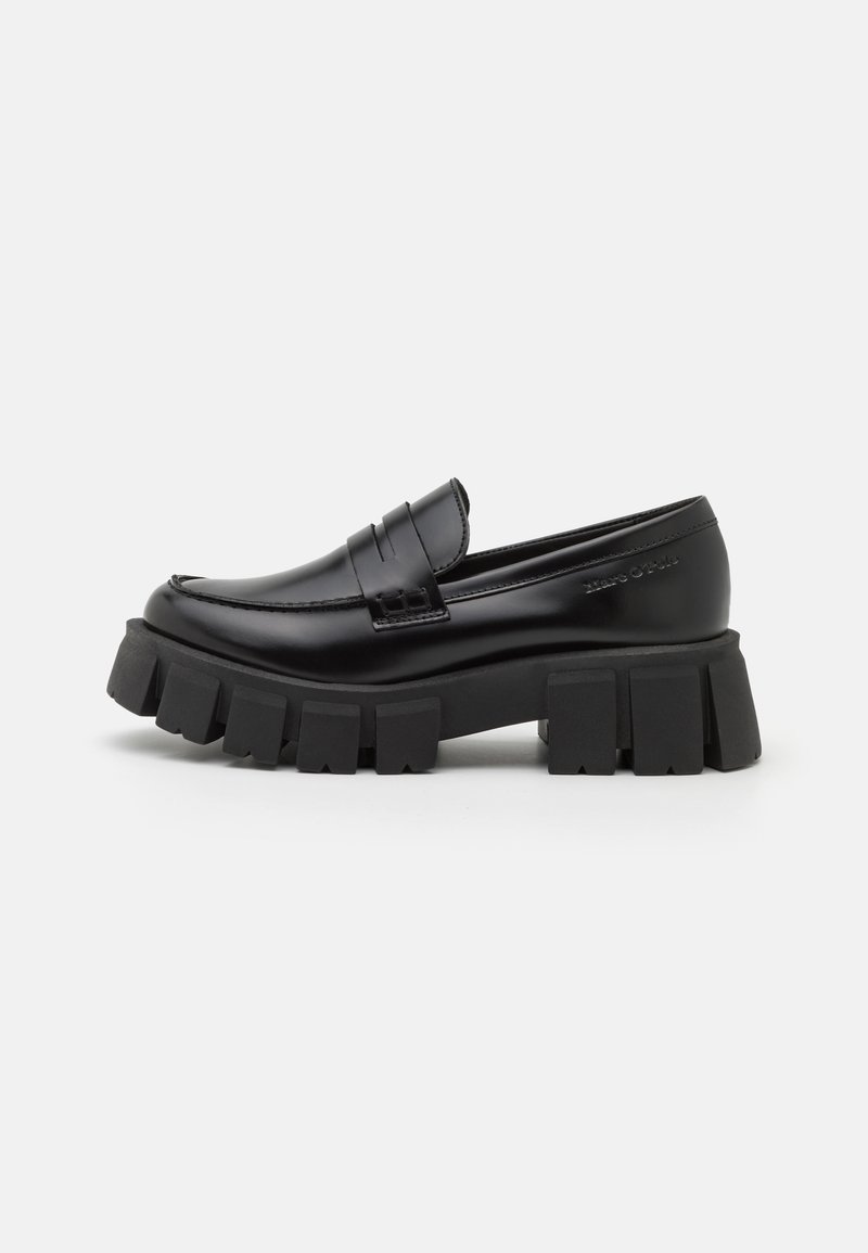Mocassin en cuir noir avec semelle crantée épaisse et bride à pièce de monnaie, profil latéral sur fond blanc.