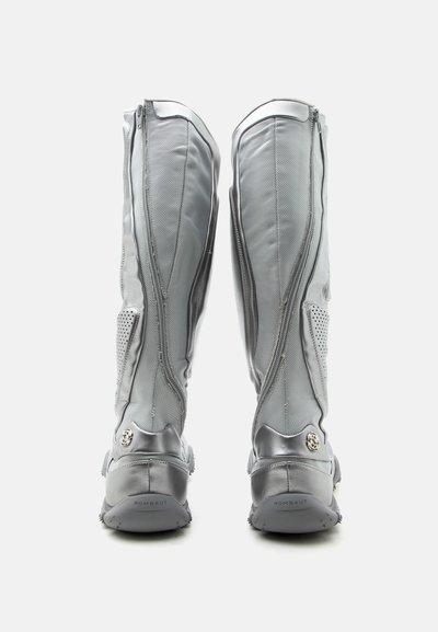 Ζευγάρι ψηλές γκρι μπότες με φερμουάρ πίσω, πάνελ από διχτυωτό ύφασμα, ενισχυμένες φτέρνες και επώνυμες σόλες, εμφανιζόμενες από πίσω σε λευκό φόντο.