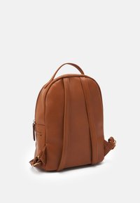 Sac à dos en cuir marron de forme arrondie, avec une poche zippée à l'avant, une poignée supérieure et deux bretelles r�églables. Texture lisse avec des accents subtils.