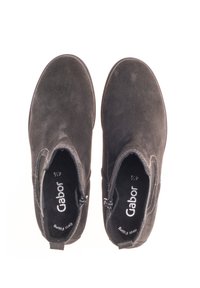 Czarne zamszowe botki za kostkę o gładkiej teksturze, z bocznymi suwakami i zaokrąglonym noskiem. Wytłoczone logo marki na wkładce.