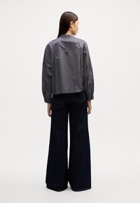 Grijze, gestreepte overhemden met een boxy fit. Gecombineerd met donkere denim, wijde jeans met stiksels en achterzakken.
