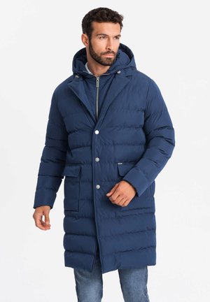 Abrigo acolchado azul marino con capucha, que presenta secciones acolchadas horizontales, dos bolsillos delanteros y detalles de botones plateados.