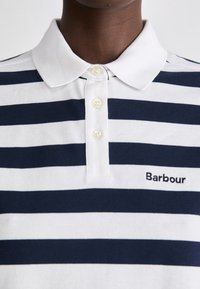 Tengerészkék és fehér csíkos pólóing, gallérral, három gombbal, és fekete hímzett "Barbour" logóval a bal mellrészén. Pamut anyag textúra.