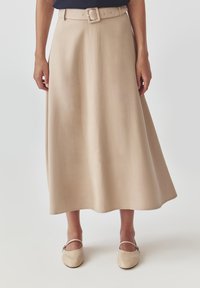 Beige A-lijn rok met een aansluitende taille en een brede riem met een vierkante gesp. Gladde textuur, knielengte, subtiel uitlopende zoom.