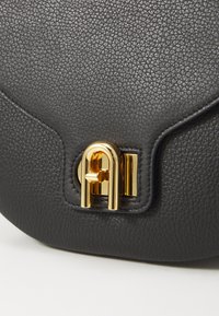 Borsa a tracolla in pelle nera con texture, caratterizzata da una chiusura in metallo dorato con un design geometrico, che evidenzia una finitura liscia e un elegante dettaglio.