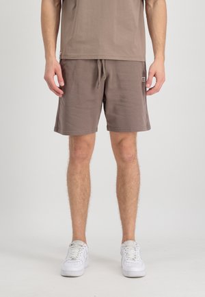Shorts marron jusqu'aux genoux en tissu doux avec une taille élastique à cordon de serrage ; associés à un t-shirt marron assorti. Baskets blanches.