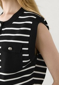 Haut sans manches à rayures noires et blanches, doté d'un col côtel�é, d'une poche poitrine avec un bouton décoratif, et d'une coupe décontractée.