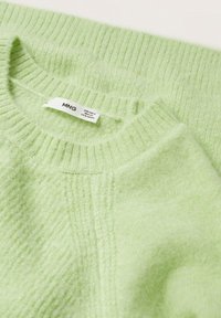Jasnozielony, miękki sweter z dzianiny z prążkowanym wykończeniem na dekolcie i mankietach. Posiada metkę z napisem „MNG” wskazującą rozmiar i instrukcje pielęgnacji.