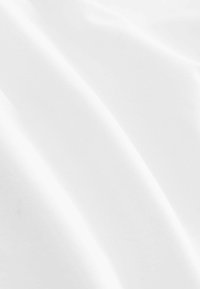 Tissu blanc avec une texture lisse et légèrement brillante, présentant des plis subtils qui créent des courbes douces et des reflets de lumière.
