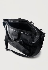 Μαύρη τσάντα ώμου από νάιλον με κλείσιμο με φερμουάρ και ρυθμιζόμενο ιμάντα ώμου, εμφανιζόμενη ανοιχτή σε λευκό φόντο.