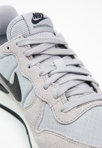 Gros plan sur une chaussure Nike Internationalist grise en suède et mesh avec le logo Nike noir sur le côté.